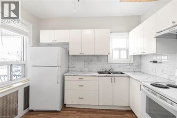 Hamilton house for rent - A white kitchen with a refrigerator, sink, and cabinets.