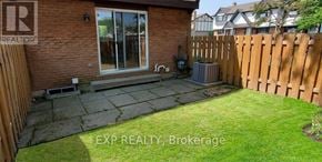 St. Catharines (Carlton/Bunting) townhouse for rent - A backyard with a wooden fence and a brick house.