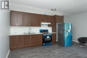 Kawartha Lakes (Ops) triplex for rent - A kitchen with brown cabinets and a blue fridge.