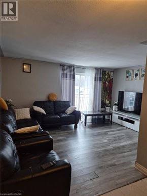 Kitchener condo for rent - A living room with a black leather couch and a television.