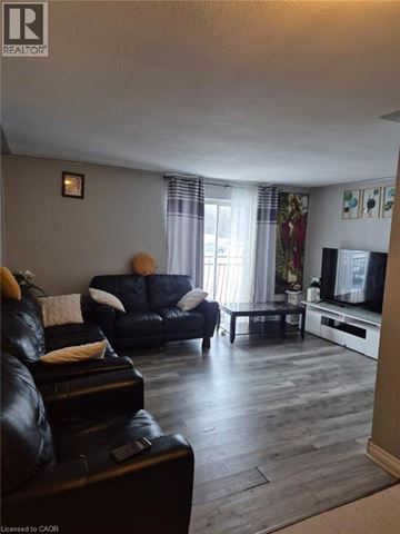 Kitchener condo for rent - A living room with a black leather couch and a television.