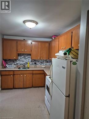 Kitchener condo for rent - A kitchen with wooden cabinets and a white fridge.