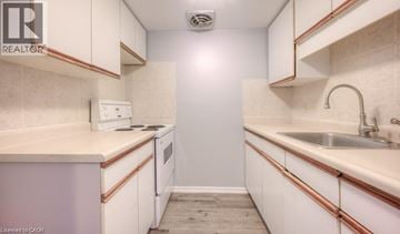 Kitchener townhouse for rent - A small, white kitchen with a sink and a refrigerator.