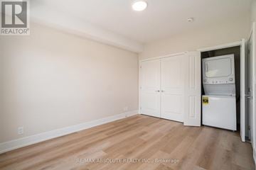 Arnprior house for rent - A white refrigerator is in a kitchen with wood floors and white cabinets.
