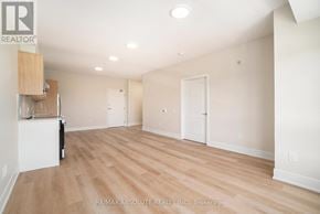 Arnprior house for rent - A spacious room with wooden flooring and white walls, with a cabinet and a chair in the corner.