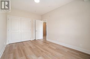Arnprior house for rent - A room with white walls and wooden flooring, with a door on the right and two closet doors on the left.