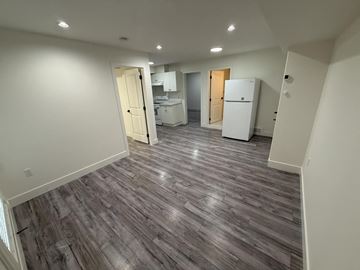 Surrey house for rent - A kitchen with a refrigerator and cabinets is visible through an open door.