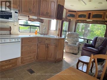 Northern Bruce Peninsula mobile home for rent - A kitchen area with wooden cabinets and a white stove.