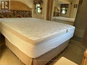 Northern Bruce Peninsula mobile home for rent - A bed with a white mattress in a room with floral wallpaper.