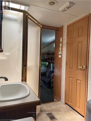 Northern Bruce Peninsula mobile home for rent - A bathroom with a sink, mirror, and wooden door.