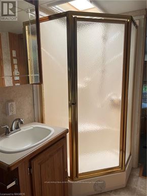Northern Bruce Peninsula mobile home for rent - A bathroom with a sink and a shower with a glass door.