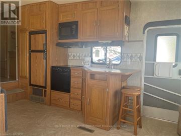 Northern Bruce Peninsula mobile home for rent - A kitchen with wooden cabinets and a black oven.