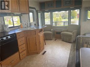 Northern Bruce Peninsula mobile home for rent - A kitchen with wooden cabinets and a black stove top oven.