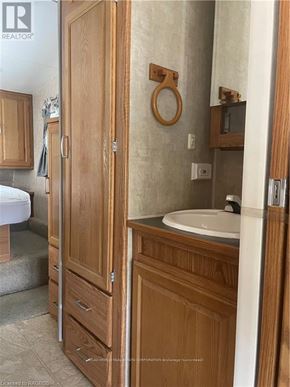 Northern Bruce Peninsula mobile home for rent - A wooden medicine cabinet with a white sink and a towel hanging on the wall.