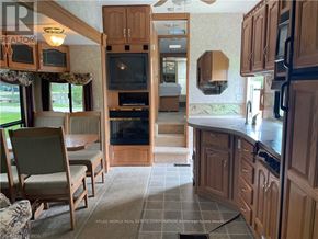 Northern Bruce Peninsula mobile home for rent - A kitchen with wooden cabinets and a black stove top oven.