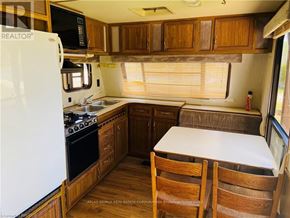Northern Bruce Peninsula mobile home for rent - A kitchen with wooden cabinets and a white fridge.