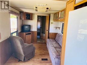 Northern Bruce Peninsula mobile home for rent - A living room with a grey couch and a television set.