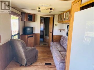 Northern Bruce Peninsula mobile home for rent - A living room with a grey couch and a television set.