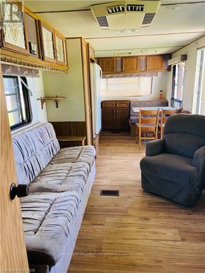 Northern Bruce Peninsula mobile home for rent - A grey couch is in the middle of a room with wooden floors and furniture.