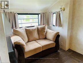Northern Bruce Peninsula mobile home for rent - A beige couch with a window behind it in a room.
