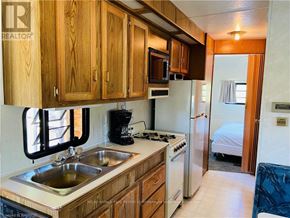 Northern Bruce Peninsula mobile home for rent - A kitchen with wooden cabinets and a stove top oven.