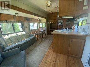 Northern Bruce Peninsula mobile home for rent - A well-lit kitchen and living room area with wooden flooring and furniture.