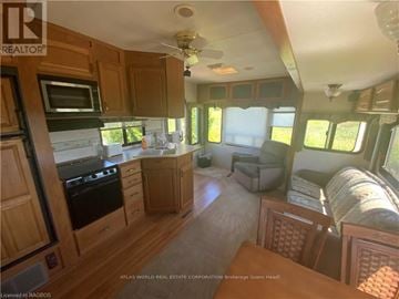 Northern Bruce Peninsula mobile home for rent - A kitchen area with wooden cabinets and a black stove top oven.