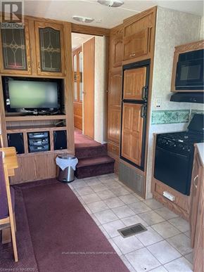 Northern Bruce Peninsula mobile home for rent - A kitchen with wooden cabinets and a black stove top oven.