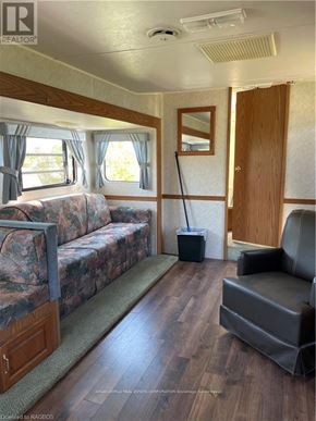 Northern Bruce Peninsula mobile home for rent - A living room with a couch, chair, and vacuum cleaner.
