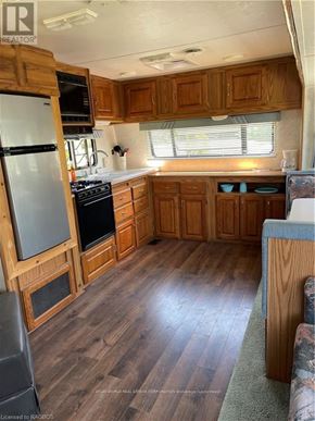Northern Bruce Peninsula mobile home for rent - A kitchen with wooden cabinets and a refrigerator.