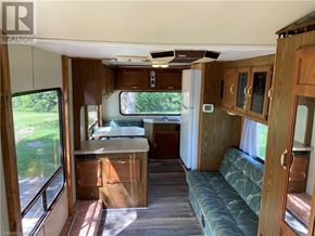 Northern Bruce Peninsula mobile home for rent - The interior of a camper van with a couch, table, and a window seat.