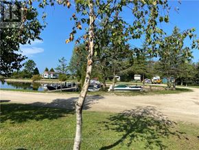 Northern Bruce Peninsula mobile home for rent - A tree in the foreground with a house and boats in the background.