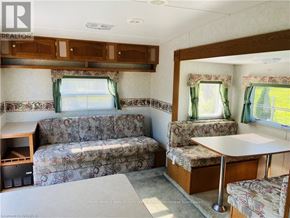 Northern Bruce Peninsula mobile home for rent - A living room with a couch, a table, and a window with a green curtain.