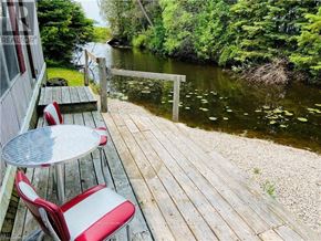 Northern Bruce Peninsula mobile home for rent - A wooden deck with a table and chairs overlooking a river.