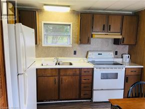 Northern Bruce Peninsula mobile home for rent - A kitchen with a white fridge, sink, and stove.