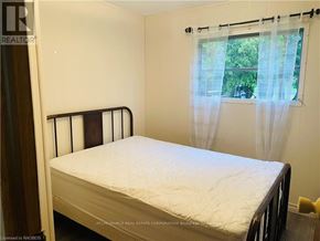 Northern Bruce Peninsula mobile home for rent - A white bed with a white mattress in a room with a window.