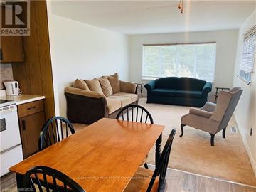 Northern Bruce Peninsula mobile home for rent - A living room with a black couch and a wooden table.