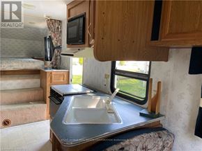 Northern Bruce Peninsula mobile home for rent - A kitchen area with a sink, stove, and microwave.