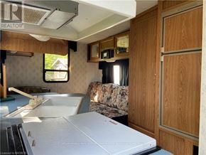 Northern Bruce Peninsula mobile home for rent - A kitchen area with a white fridge and wooden cabinets.