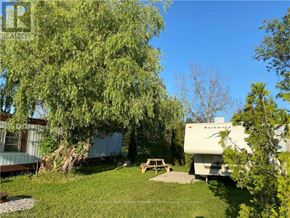 Northern Bruce Peninsula mobile home for rent - A white RV is parked in a grassy area next to a picnic table.