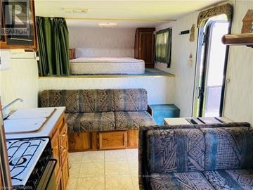 Northern Bruce Peninsula mobile home for rent - A living room with a couch and a bed in a trailer.