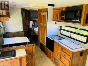 Northern Bruce Peninsula mobile home for rent - A kitchen area with wooden cabinets and a microwave.