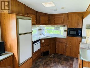 Northern Bruce Peninsula mobile home for rent - A kitchen with wooden cabinets and a white refrigerator.