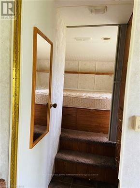 Northern Bruce Peninsula mobile home for rent - A bedroom with a bed and stairs leading to the second floor.
