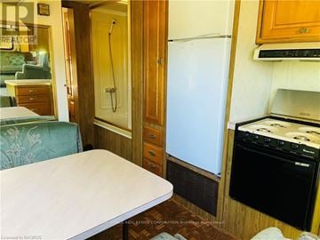 Northern Bruce Peninsula mobile home for rent - A small kitchen with a fridge, oven and a table.