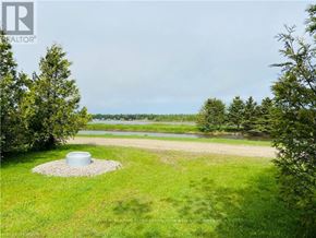 Northern Bruce Peninsula mobile home for rent - A well-maintained lawn with a pond and trees in the distance.