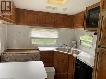 Northern Bruce Peninsula mobile home for rent - A kitchen area with wooden cabinets and a white countertop.