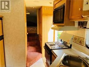 Northern Bruce Peninsula mobile home for rent - A kitchen area with a sink, stove, and microwave.