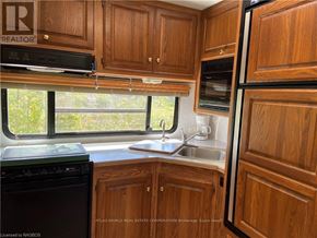 Northern Bruce Peninsula mobile home for rent - A kitchen with wooden cabinets and a black dishwasher.