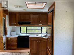 Northern Bruce Peninsula mobile home for rent - A kitchen area with wooden cabinets and a black dishwasher.